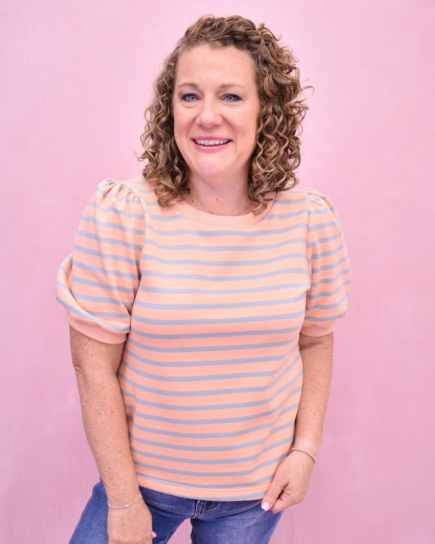 Woman wearing a striped shirt against a pink background