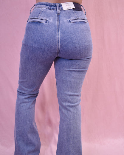 Blue jeans being worn on a pink background