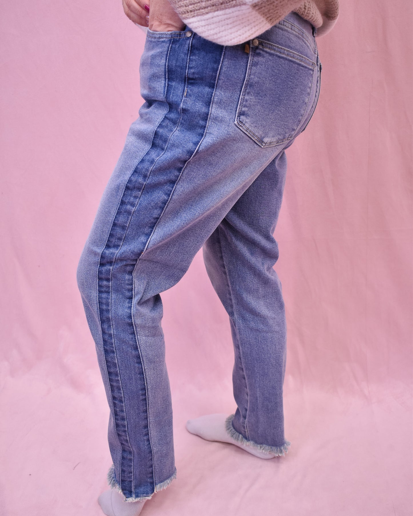Person wearing blue jeans on a pink background