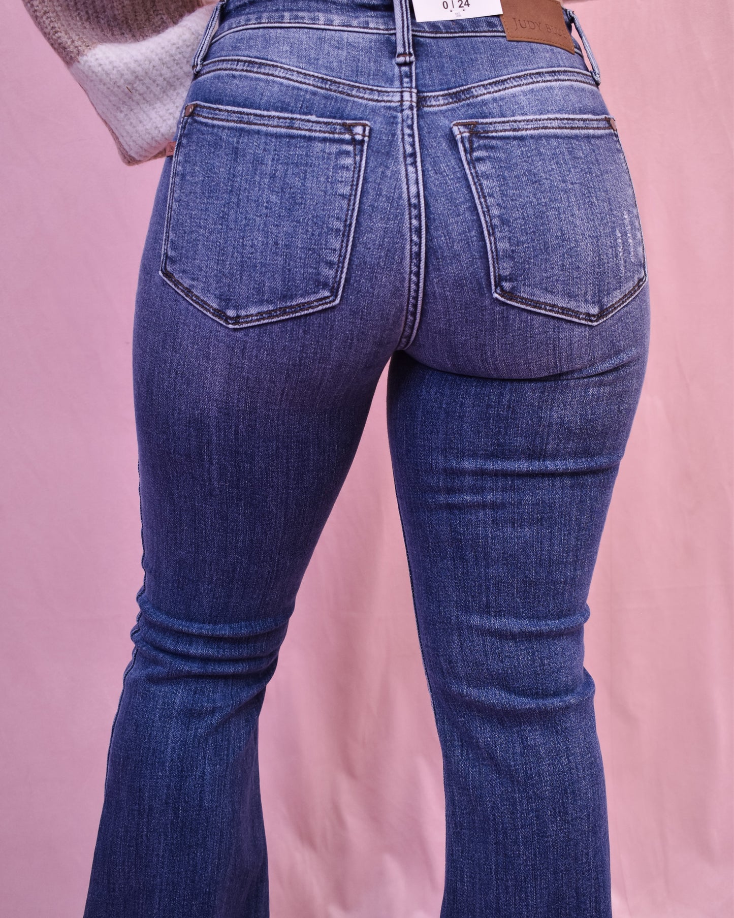 Blue jeans on a person against a pink background