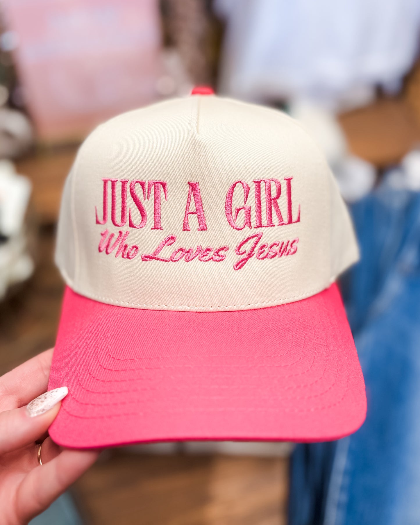 Cap with 'Just a Girl Who Loves Jesus' text held by a person.