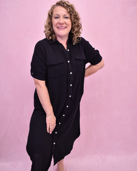 Woman wearing a black dress with white buttons against a pink background