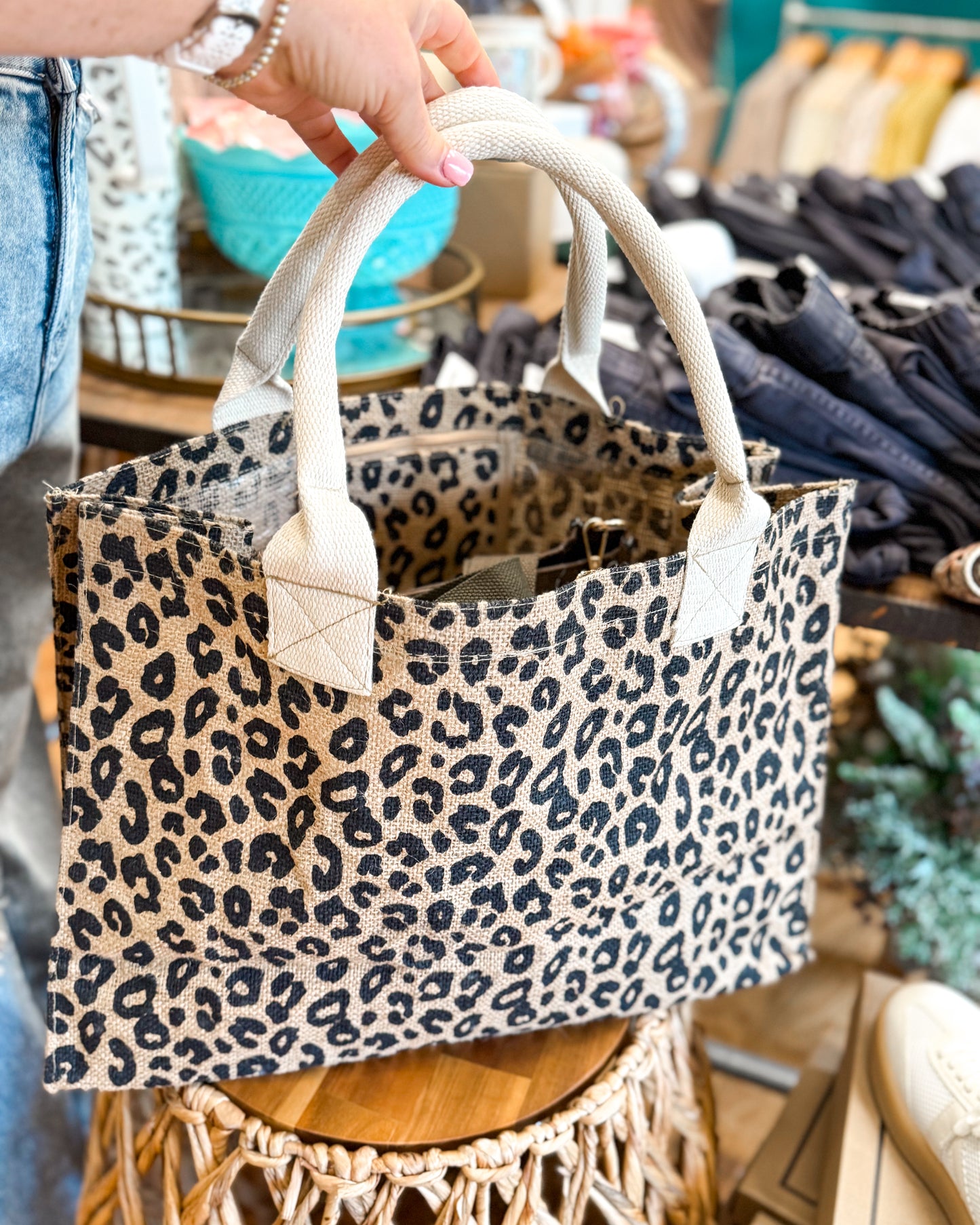 Leopard print tote bag held by a person in a store setting