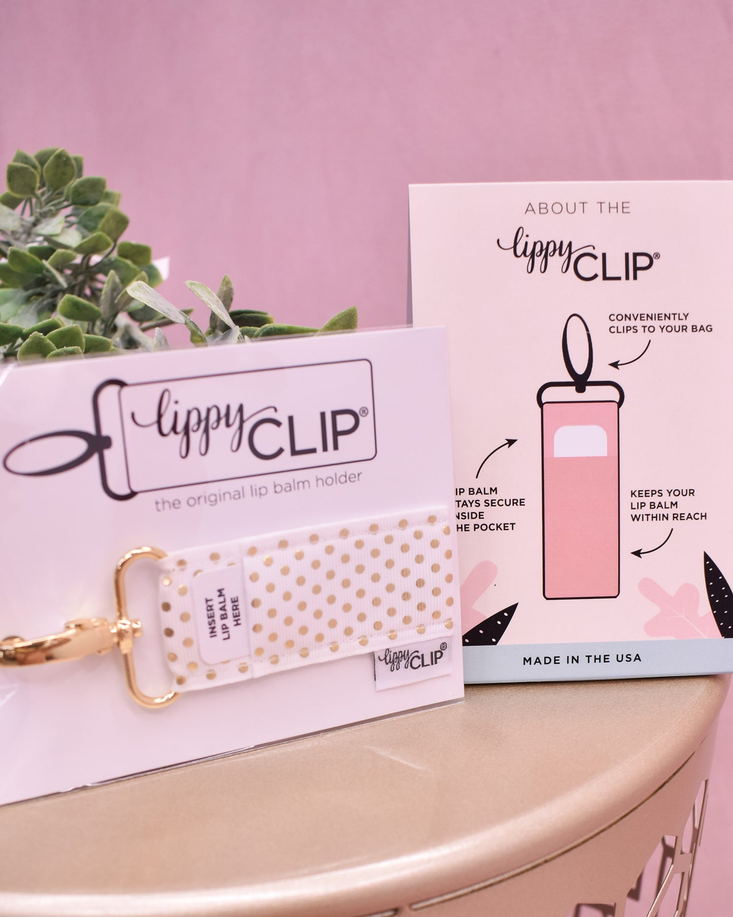 Lippy Clip product with packaging and a plant on a pink background