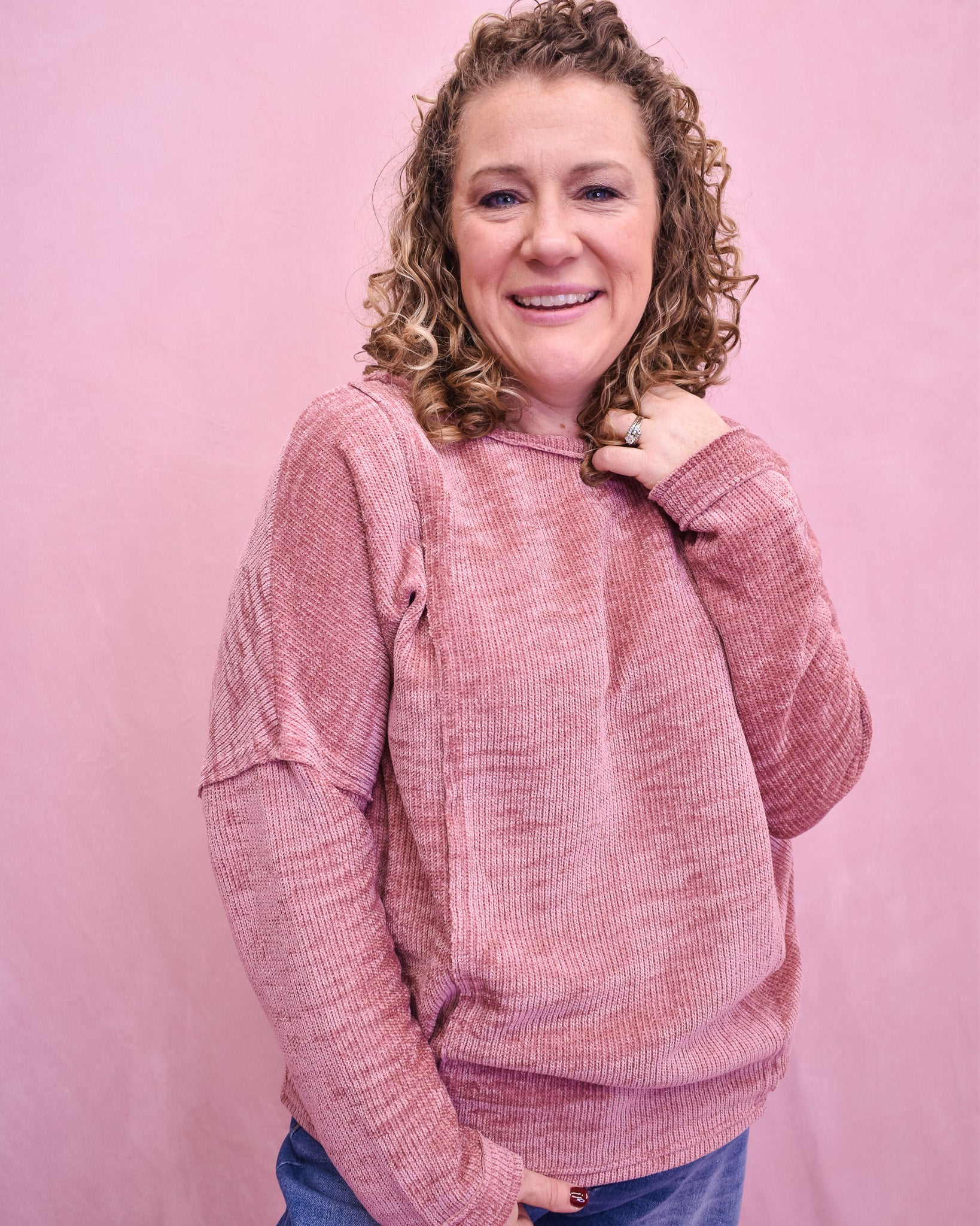 Woman wearing a pink textured sweater against a pink background