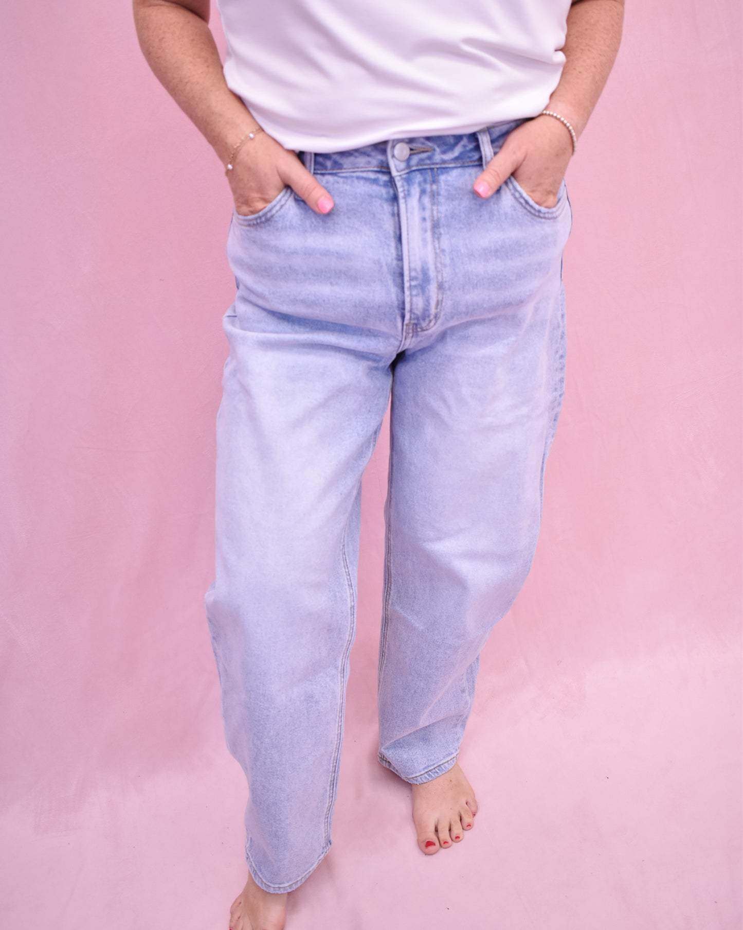 Light blue jeans worn by a person on a pink background