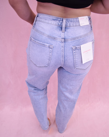 Light blue jeans with a tag on a pink background