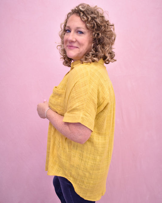 Woman wearing a yellow shirt against a pink background