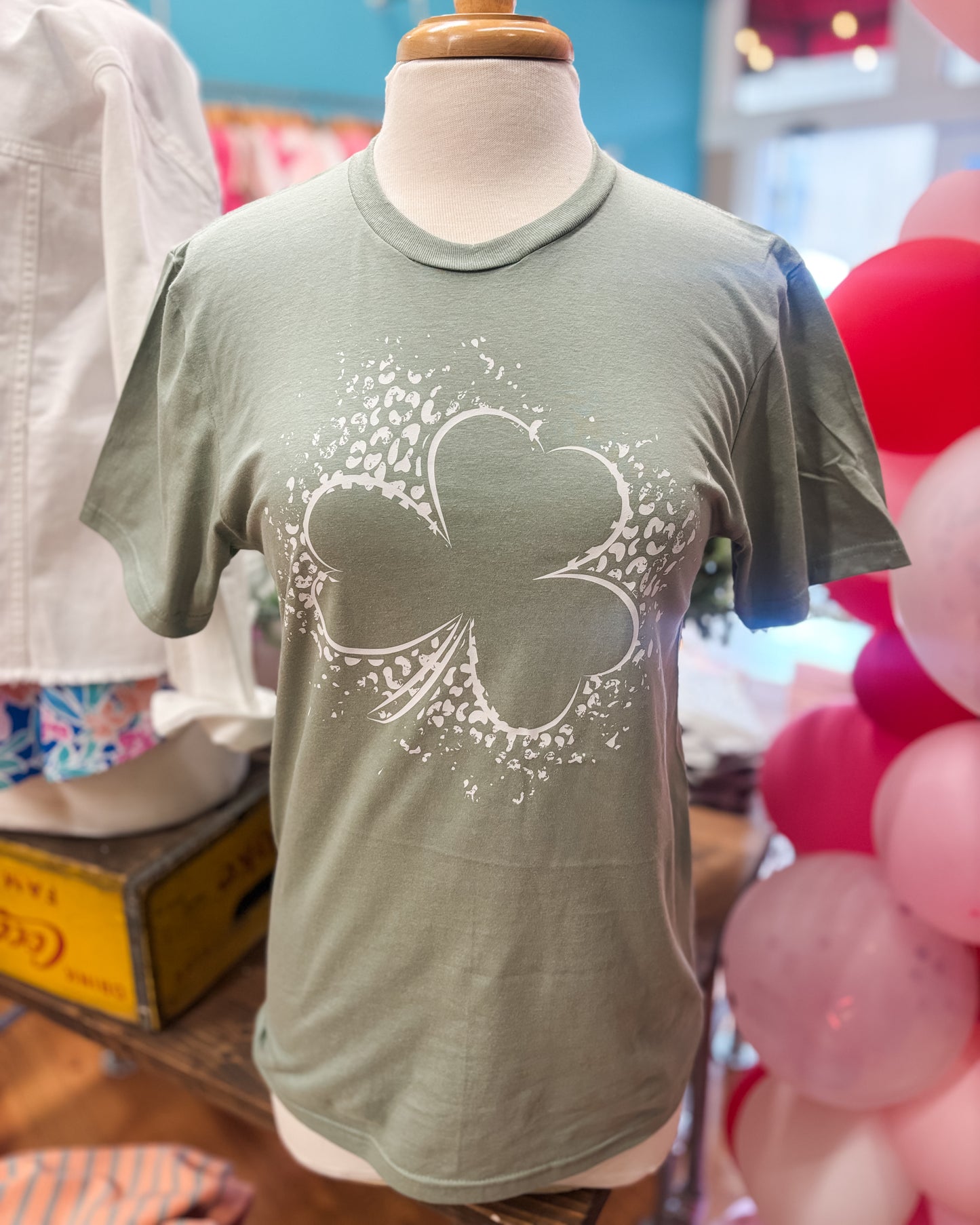 White shamrock on leopard distressed background pressed on a sage green tee.
