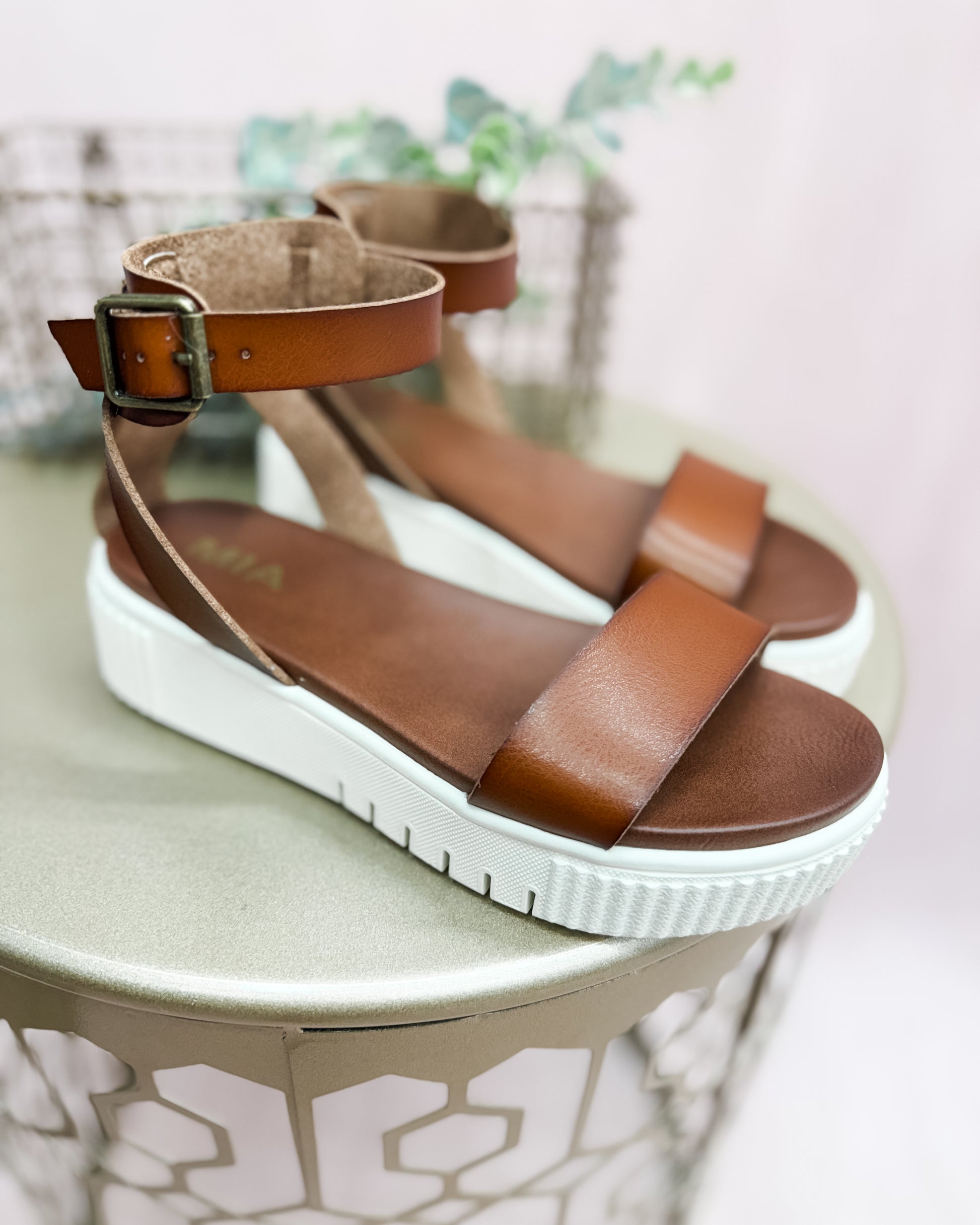 Brown platform sandals on a round surface with a light background