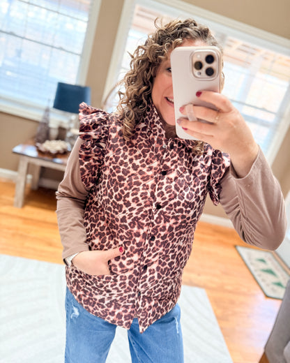 Person wearing a leopard print top and blue jeans, taking a mirror selfie.