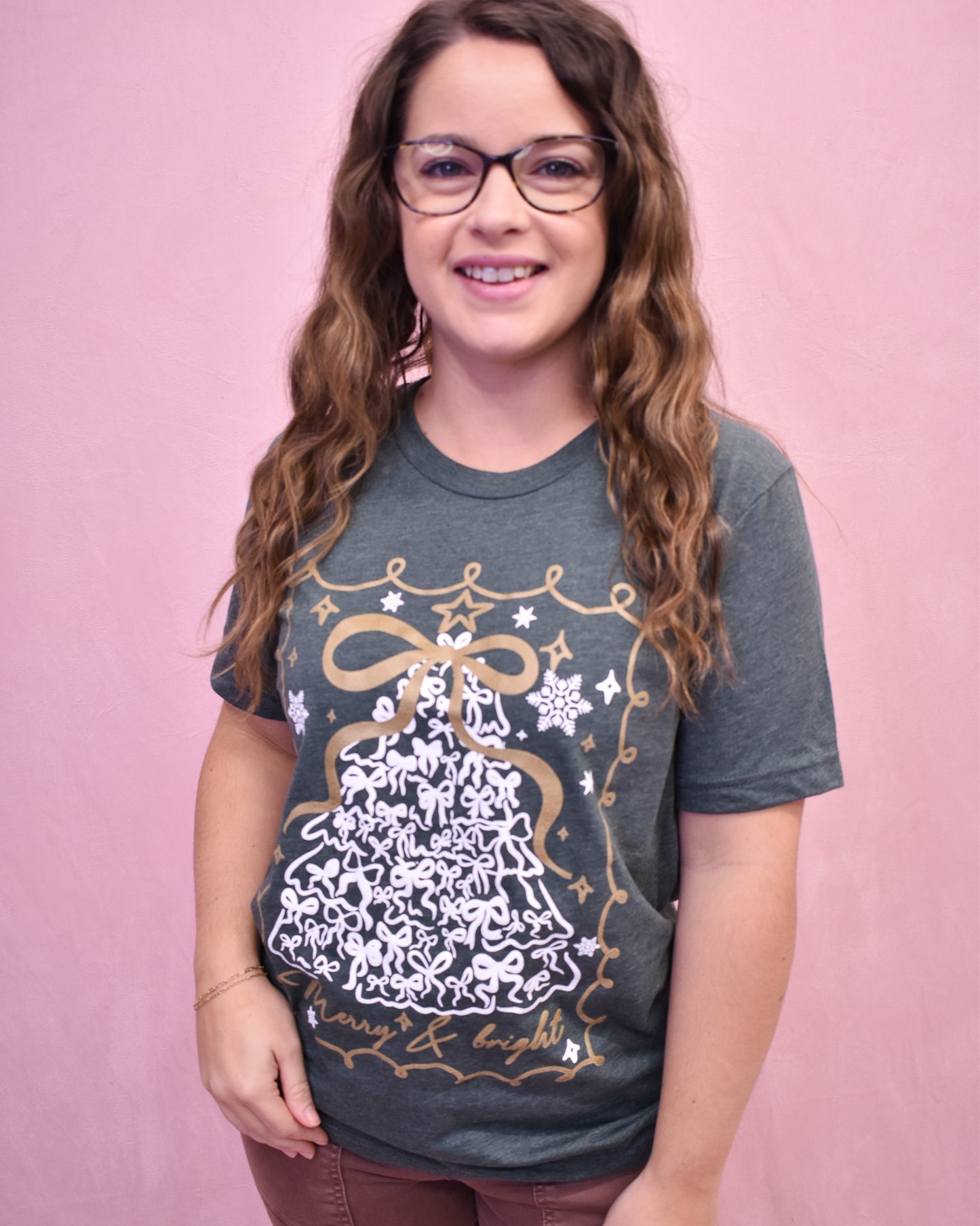 Woman wearing a dark green t-shirt with a decorative design on a pink background