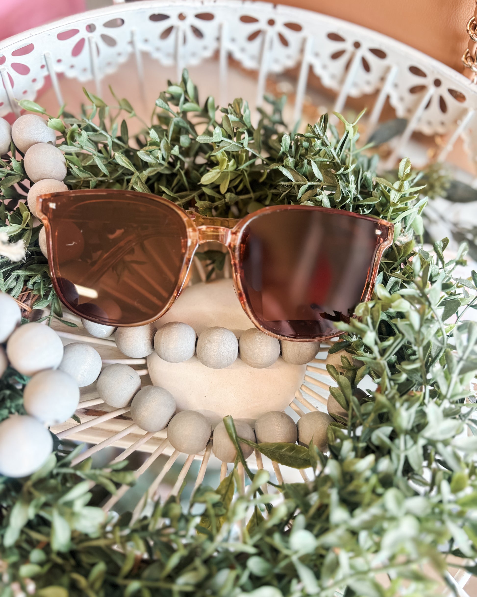 Sunglasses on a decorative wreath with greenery and beads