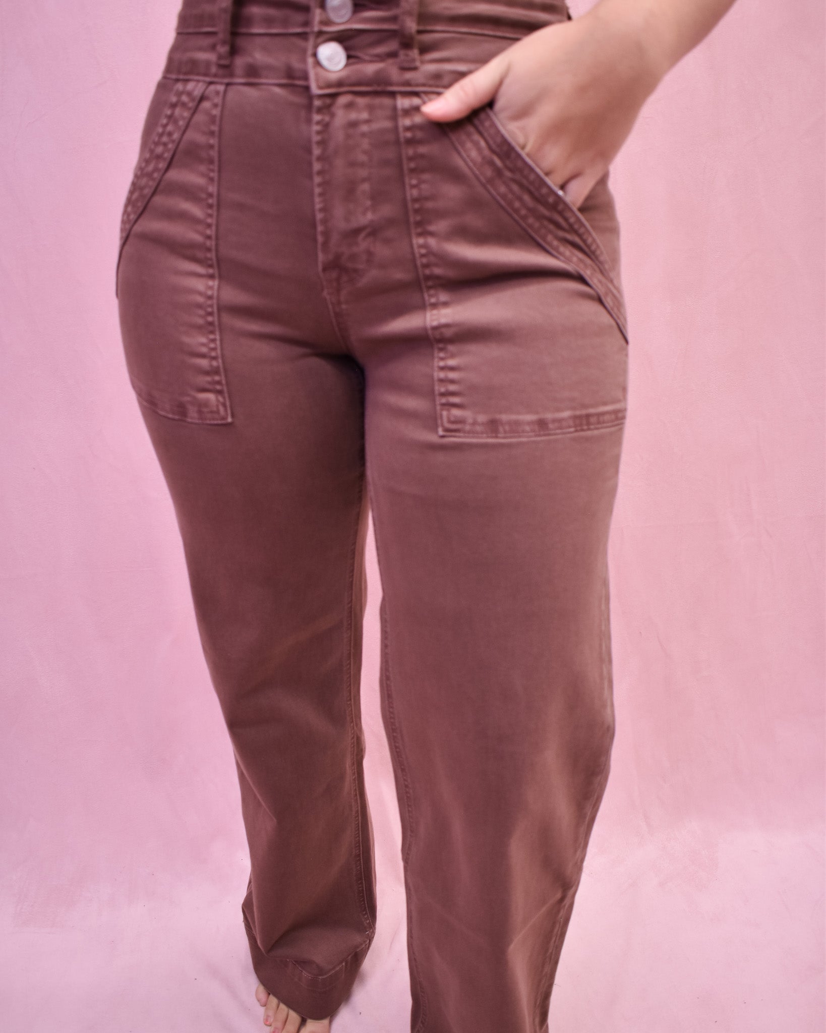 Brown pants worn by a person on a pink background