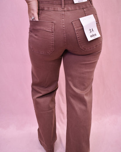 Brown pants with a size tag on a pink background