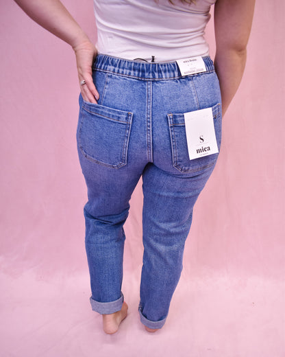 Blue jeans with a visible brand tag on a pink background