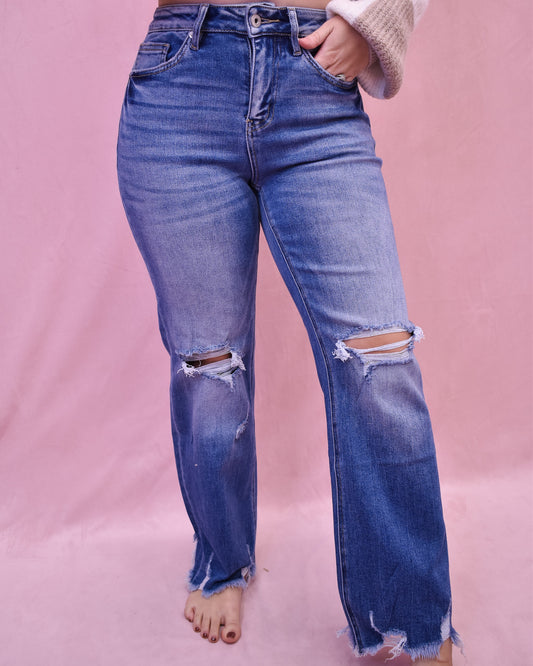 Blue jeans with distressing on a pink background