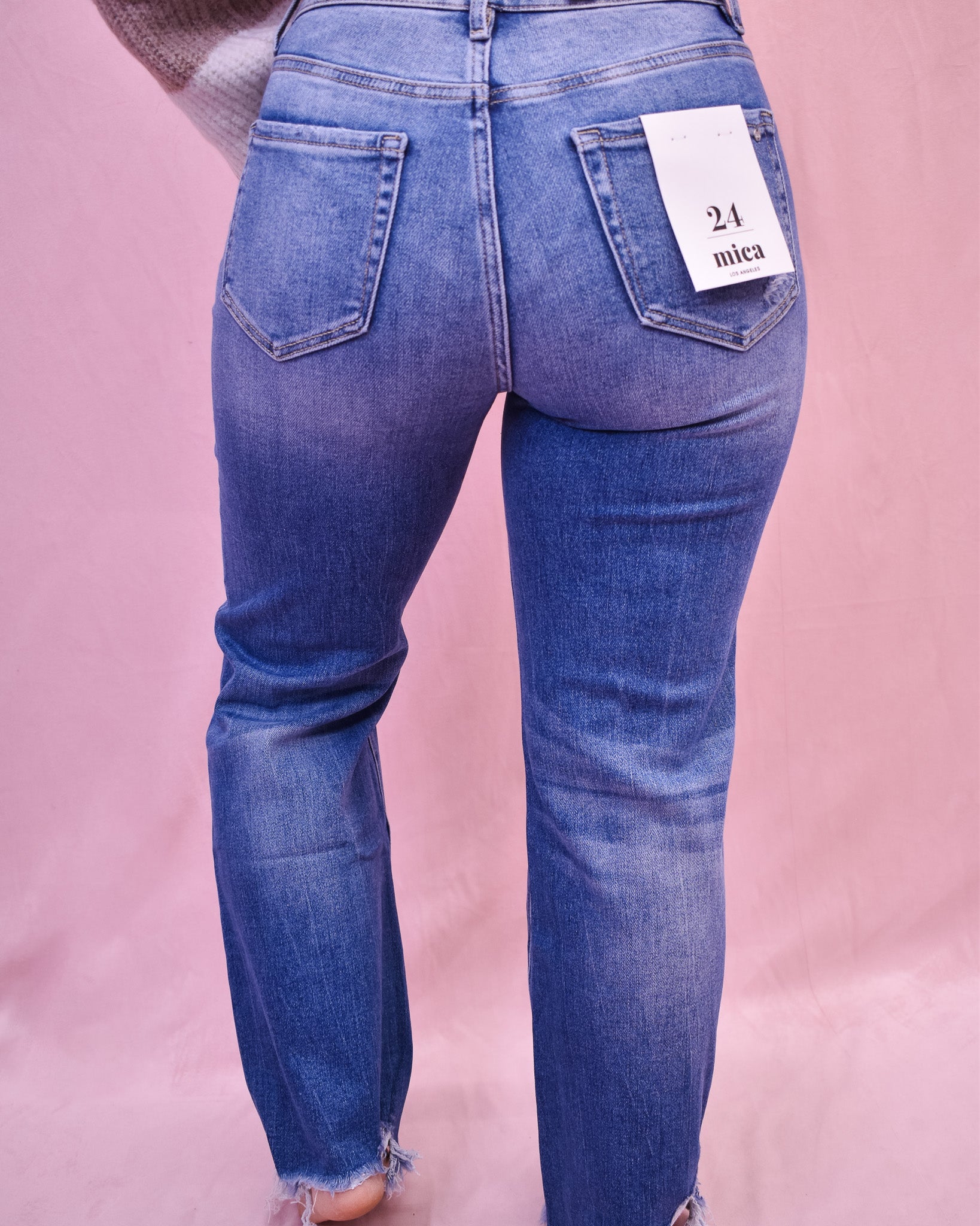 Blue jeans with a size tag on a pink background