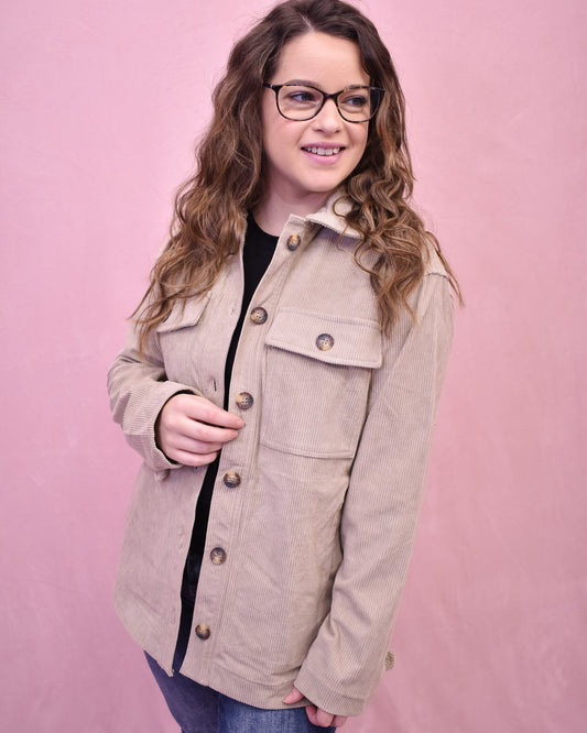 Woman wearing a beige jacket against a pink background