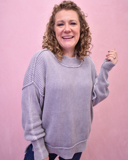 Woman wearing a light purple sweater against a pink background