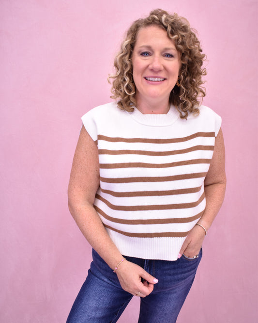 Woman wearing a white and brown striped shirt against a pink background