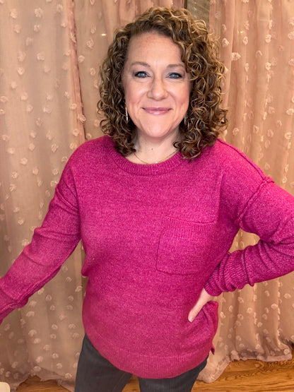 A woman wearing a pink hi-low sweater with a round neck.