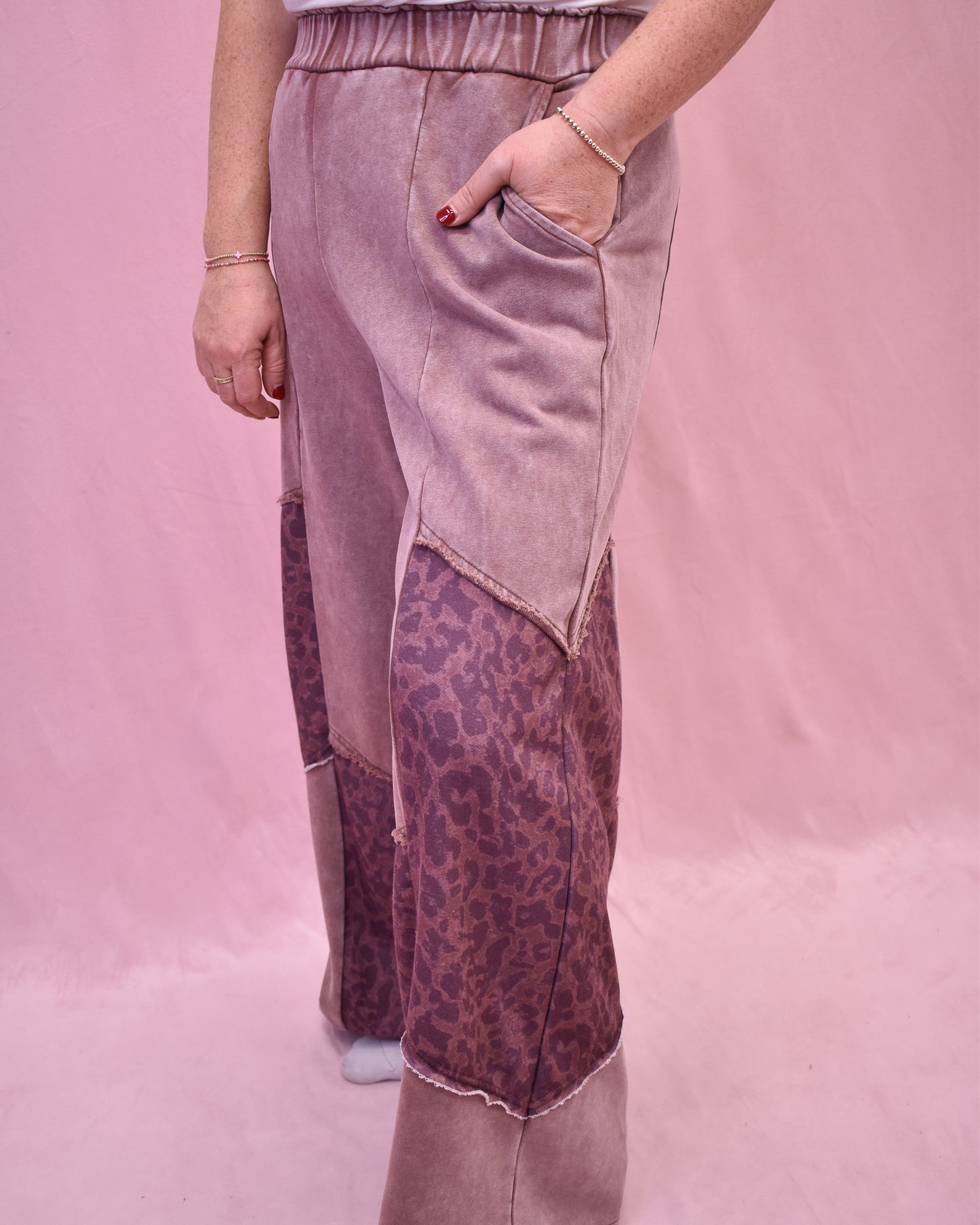 Person wearing a pink and leopard print pants with a plain pink background