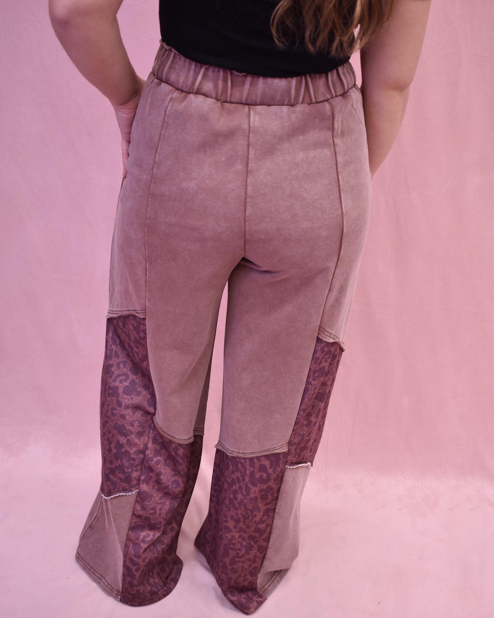 Person wearing a pair of patchwork pants with a pink background