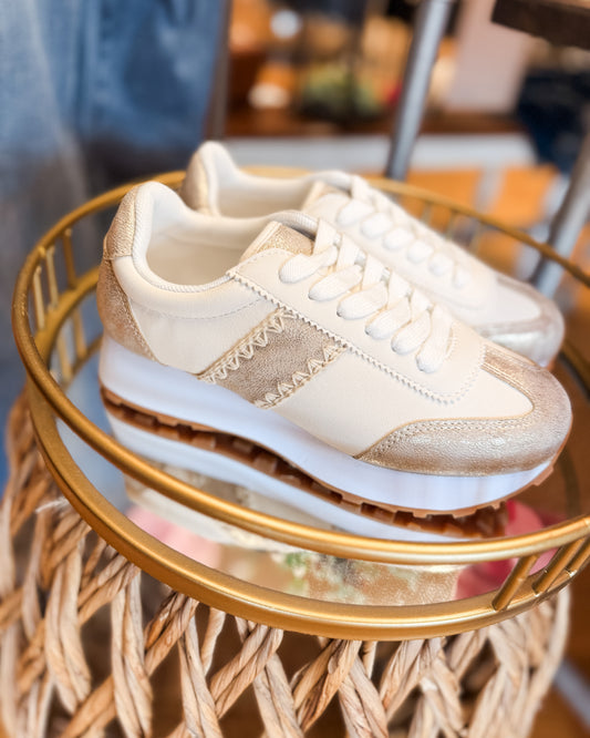 Pair of beige sneakers on a round glass table with a blurred background
