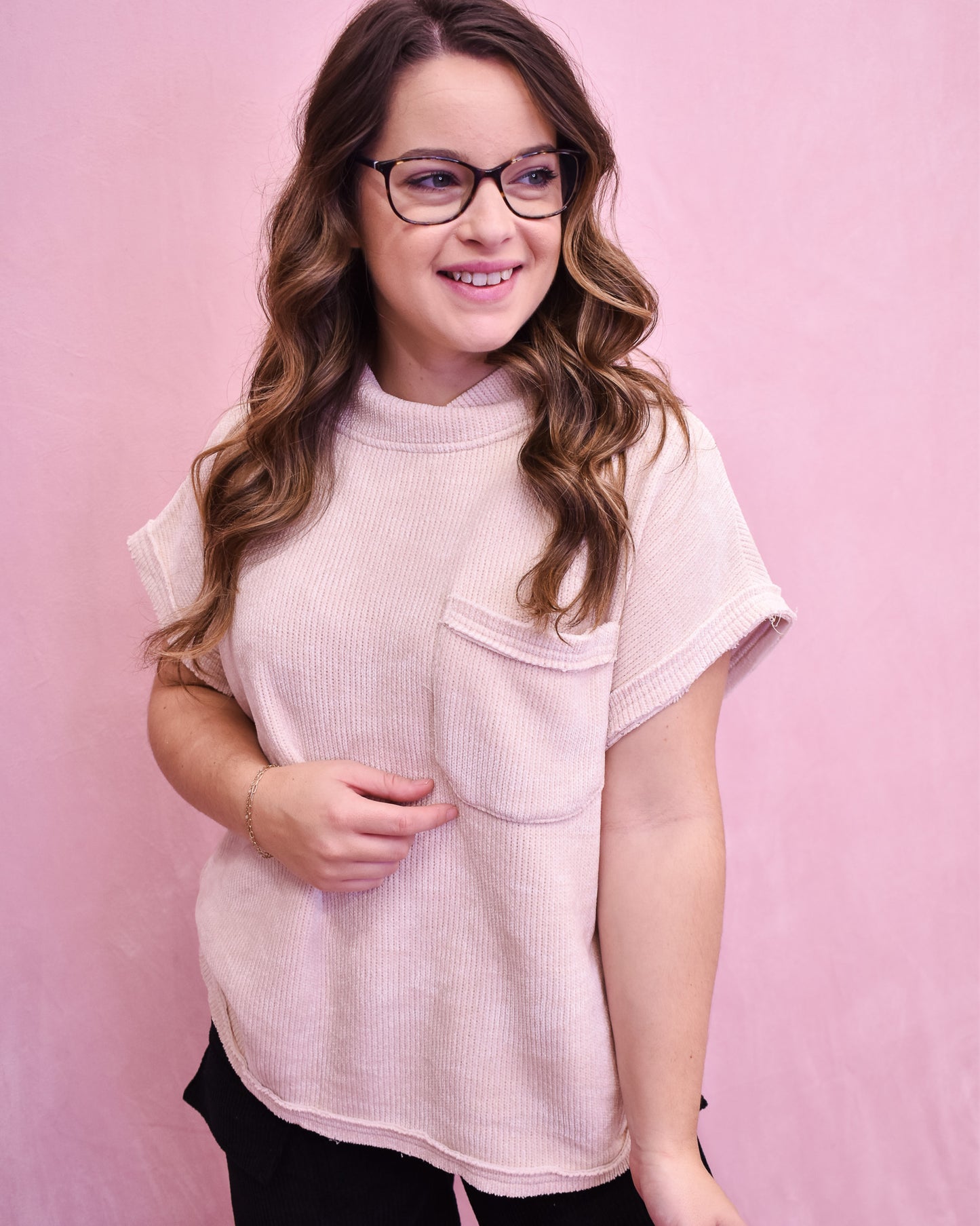 Woman wearing a light pink sweater against a pink background