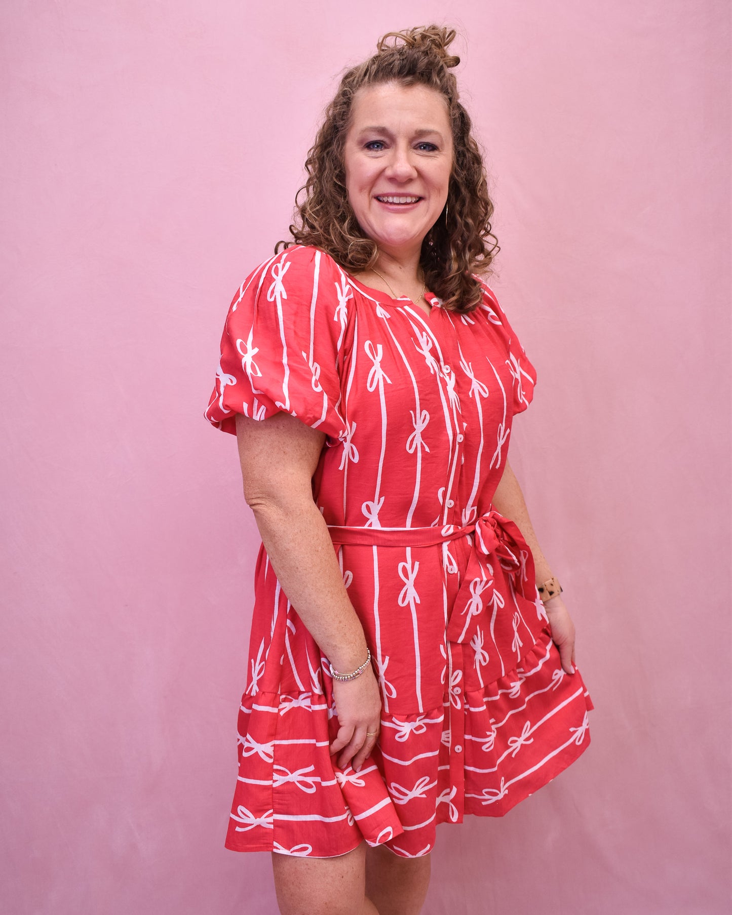 Puff sleeve hot pink dress with buttons down the front and a tie at the waist and bow detail design.