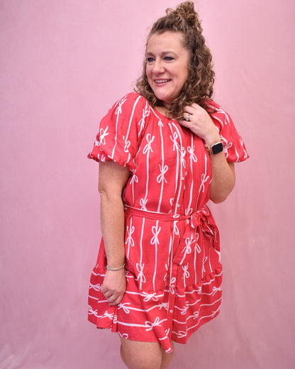 Puff sleeve hot pink dress with buttons down the front and a tie at the waist and bow detail design.