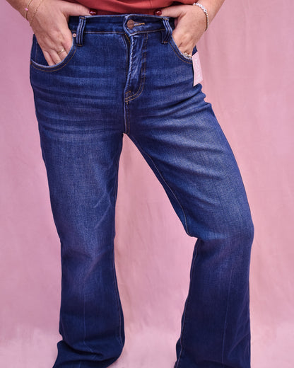 Person wearing blue jeans against a pink background