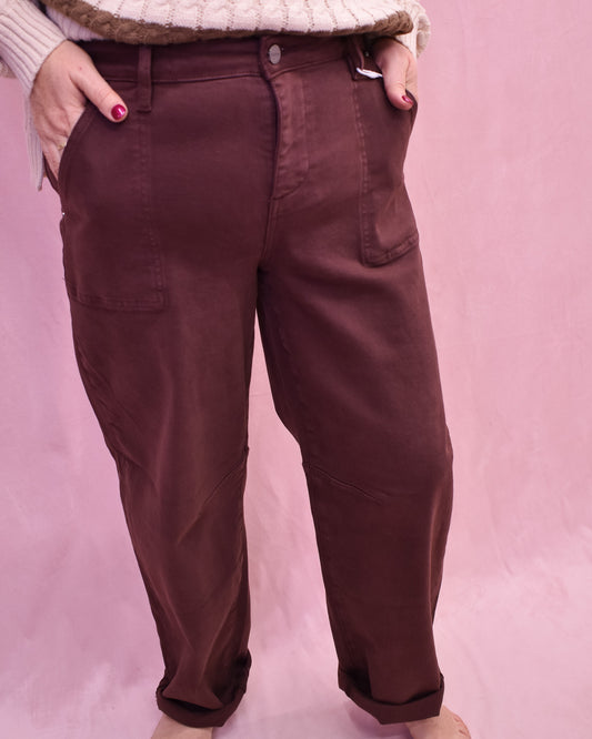 Brown pants worn by a person on a pink background