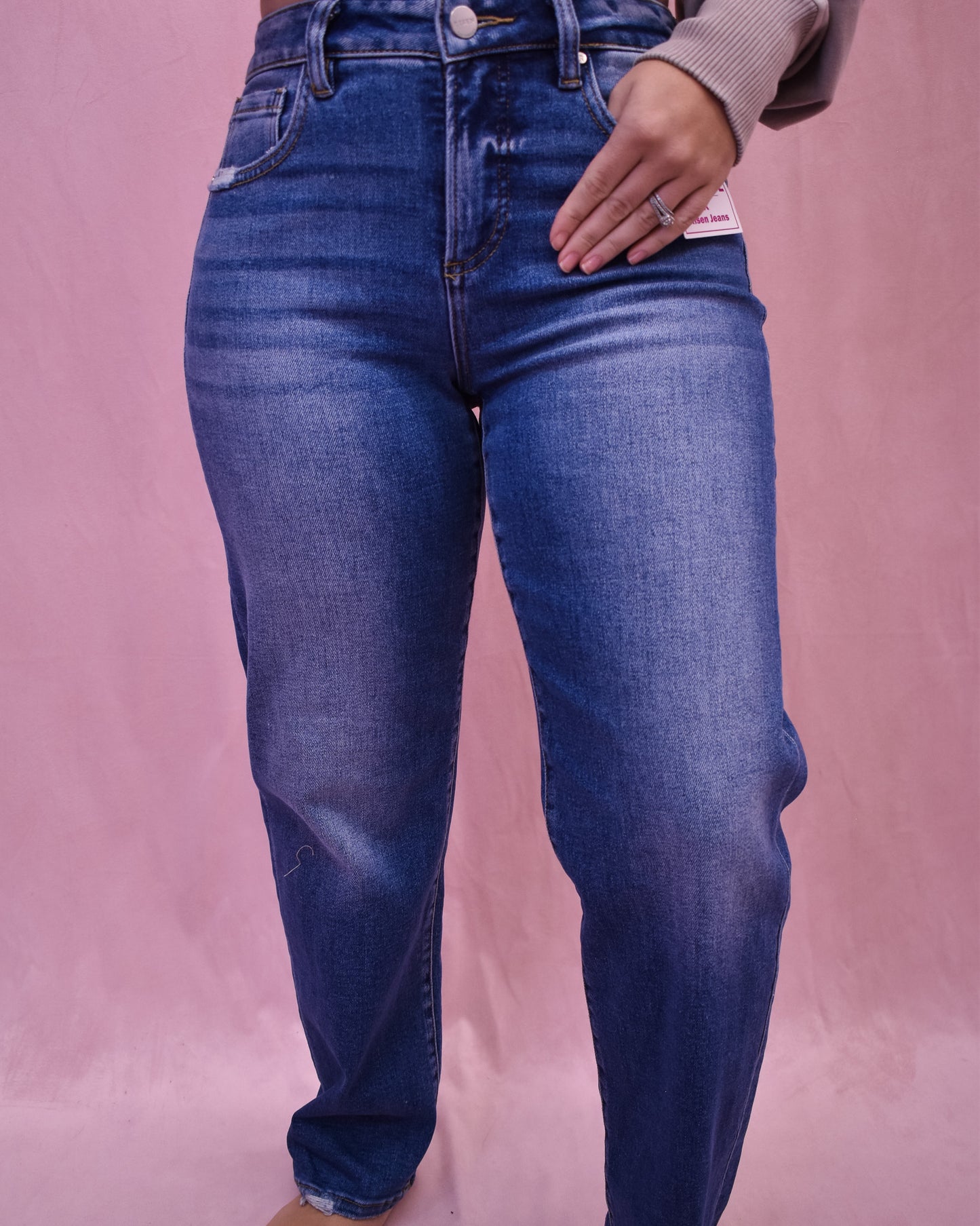 Person wearing blue jeans on a pink background