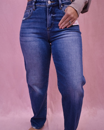 Person wearing blue jeans on a pink background