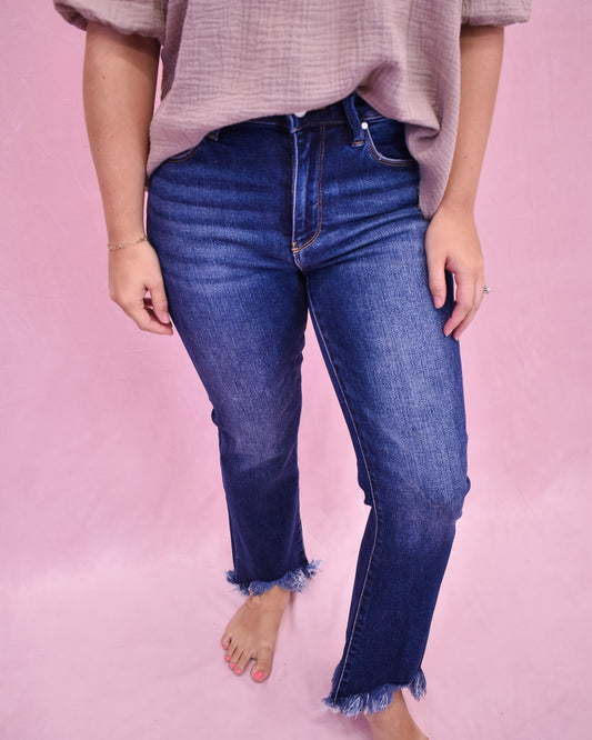 Person wearing blue jeans and a light pink top on a pink background