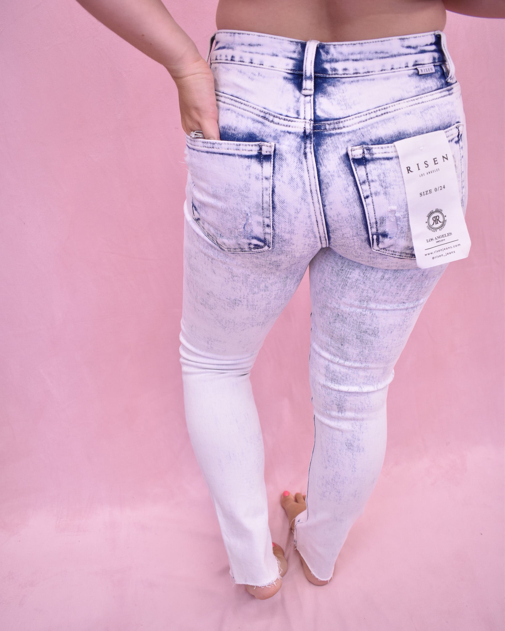 White acid-wash jeans on a pink background