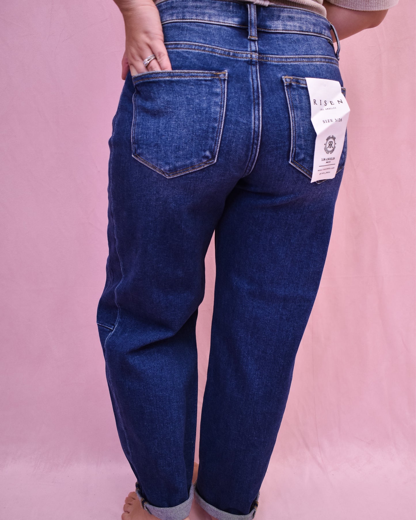 Blue jeans with a brand tag on a pink background