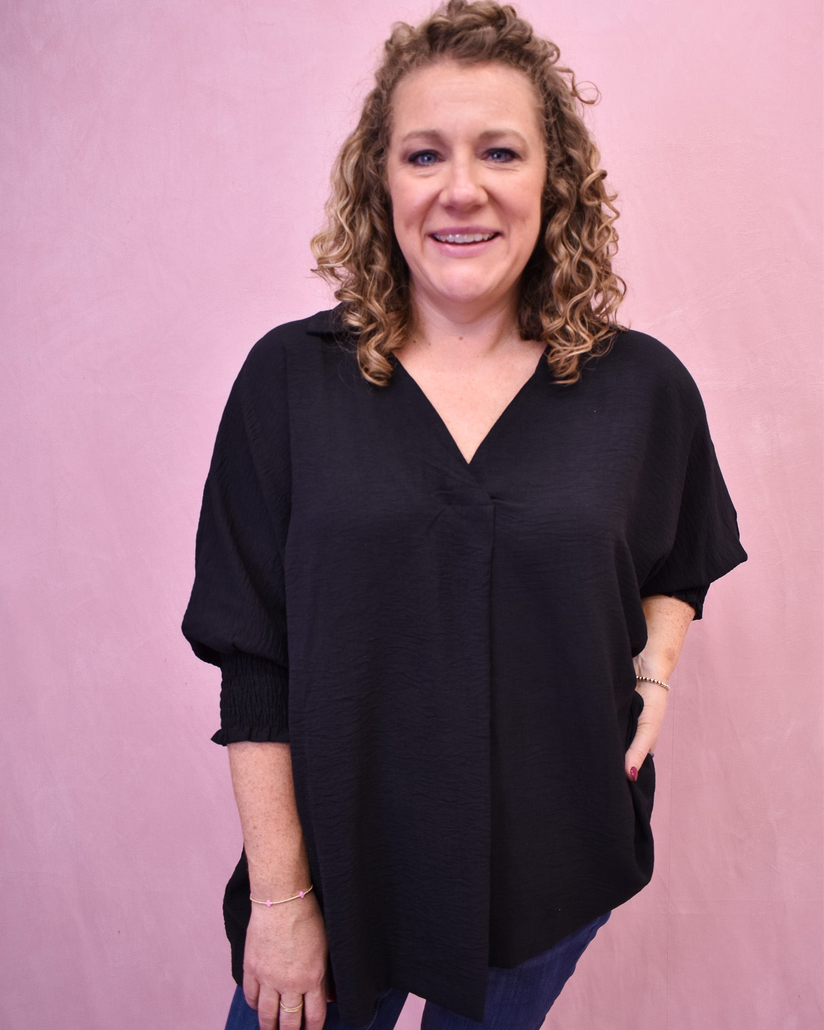 Woman wearing a black blouse against a pink background