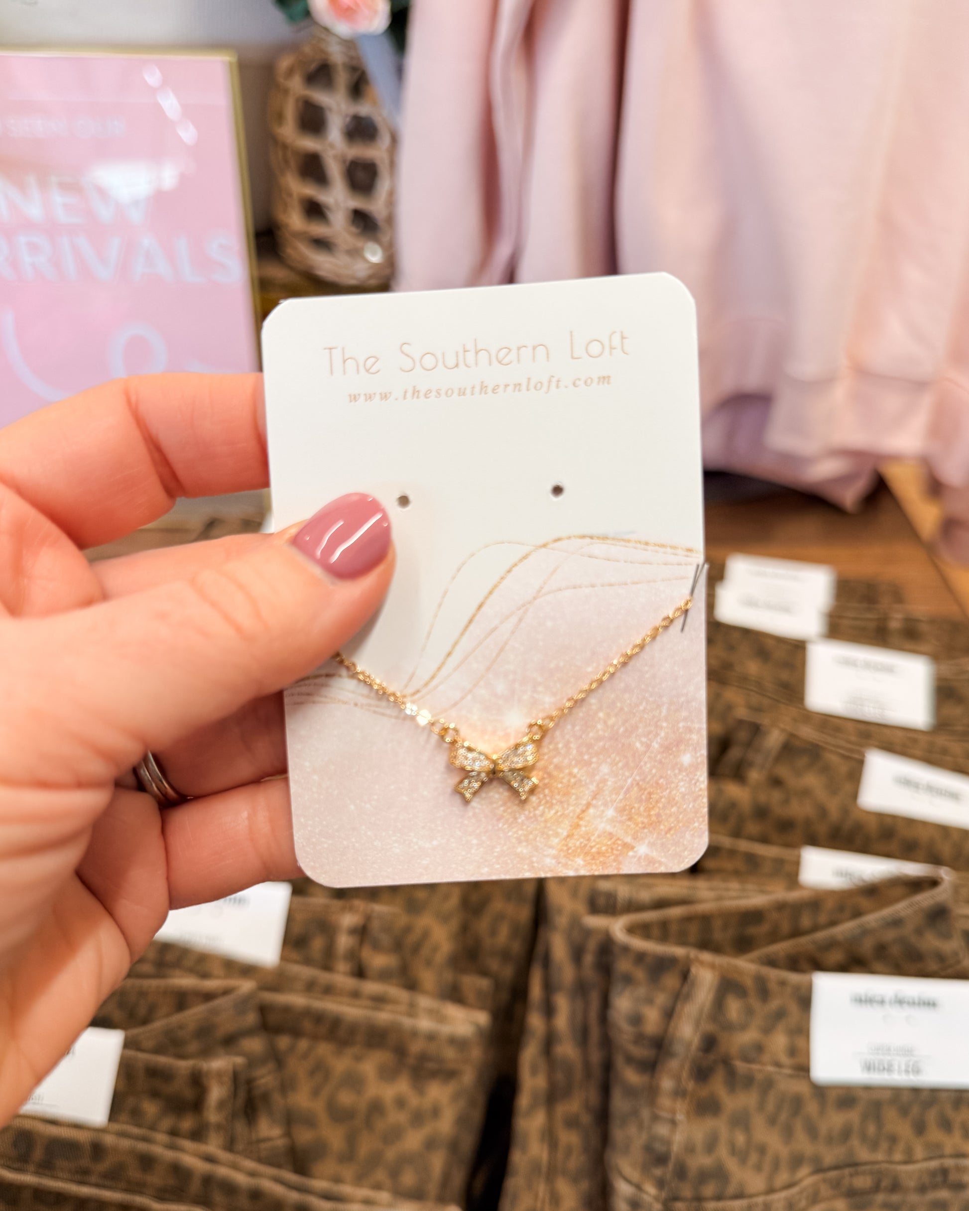 Gold necklace on a 'The Southern Loft' card held by a hand with pink nail polish.