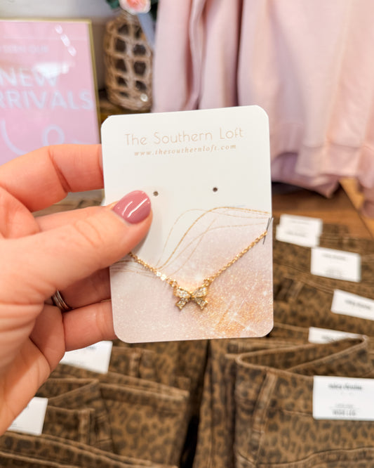 Gold necklace on a 'The Southern Loft' card held by a hand with pink nail polish.
