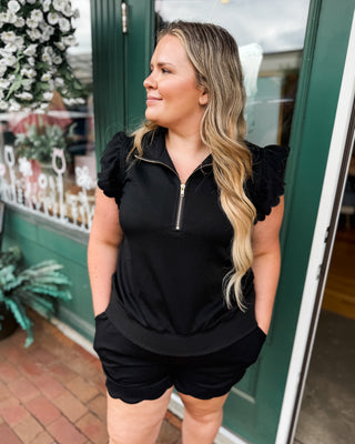 Soft Luxe-Cotton two-piece short set featuring a ruffled half-zip sweatshirt and matching shorts. A comfortable, feminine lounge set perfect for travel, errands, and everyday casual style.