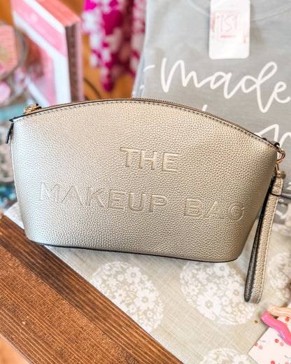 Gold makeup bag with 'THE MAKEUP BAG' text on a textured surface.