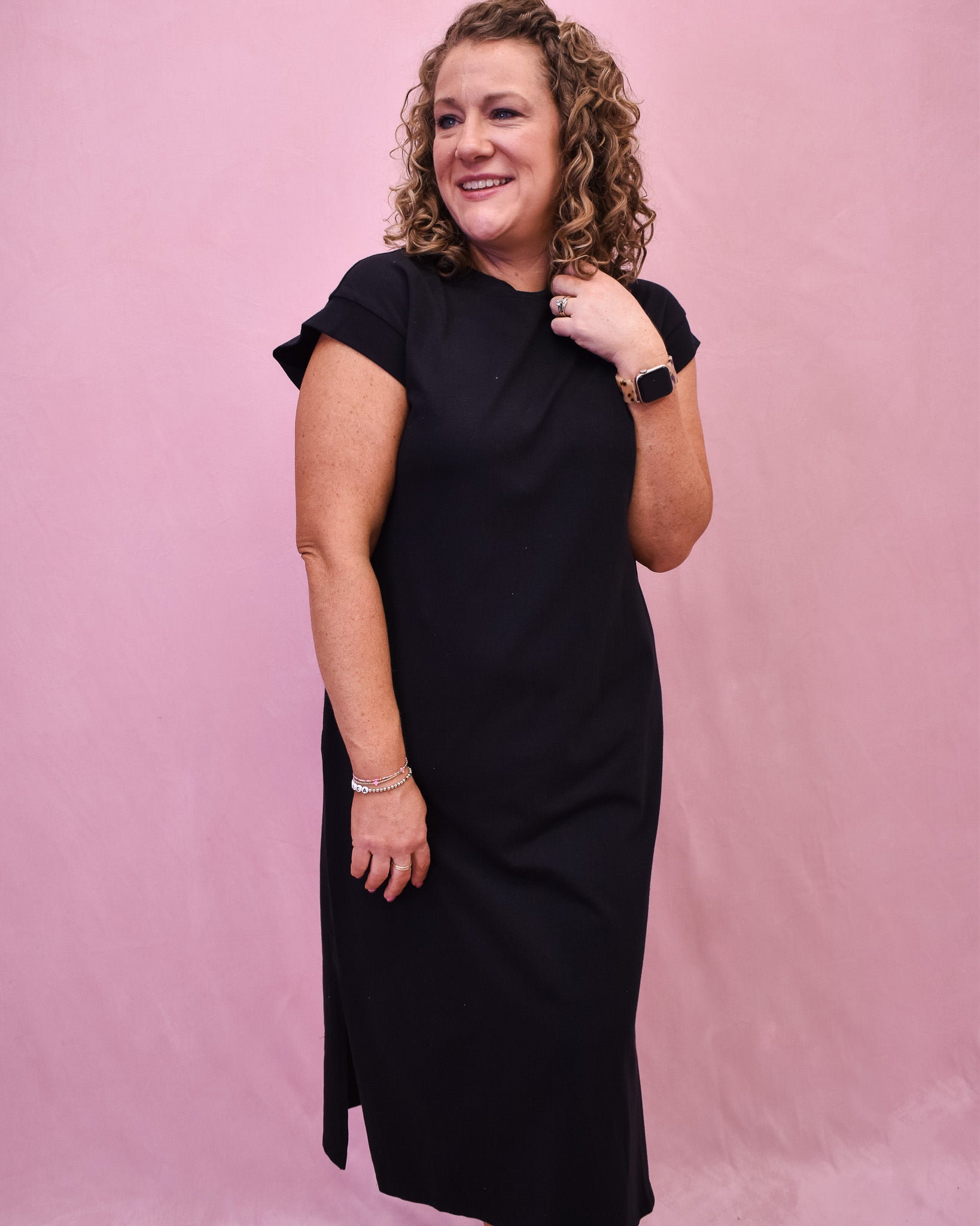 A black midi style dress with rolled sleeve and side slit.