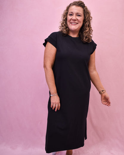 a black midi style dress with rolled short sleeves and side slit.