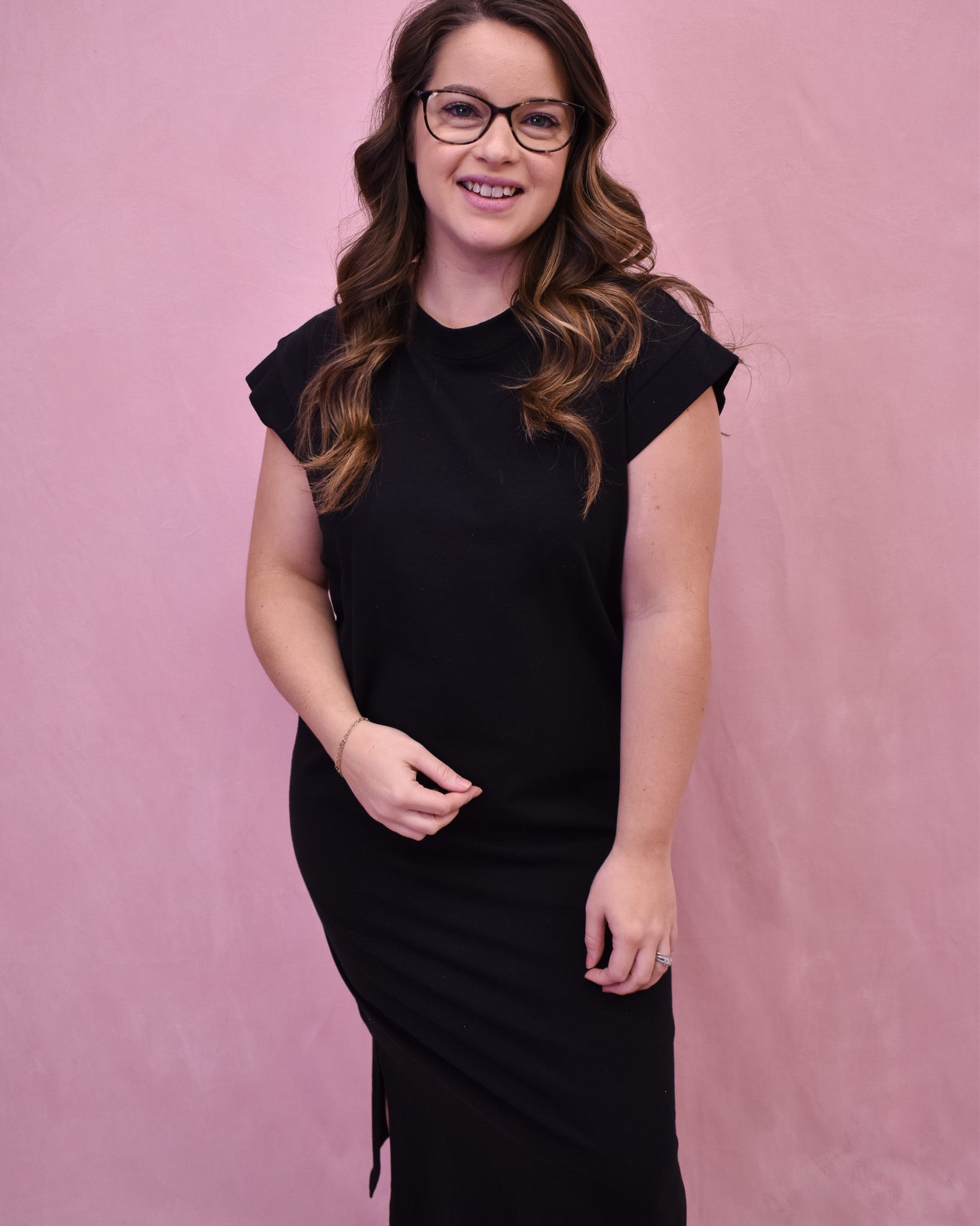 A black midi style dress with rolled sleeves and side slit.