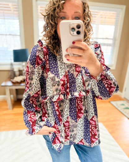 Person wearing a colorful patterned shirt taking a mirror selfie.