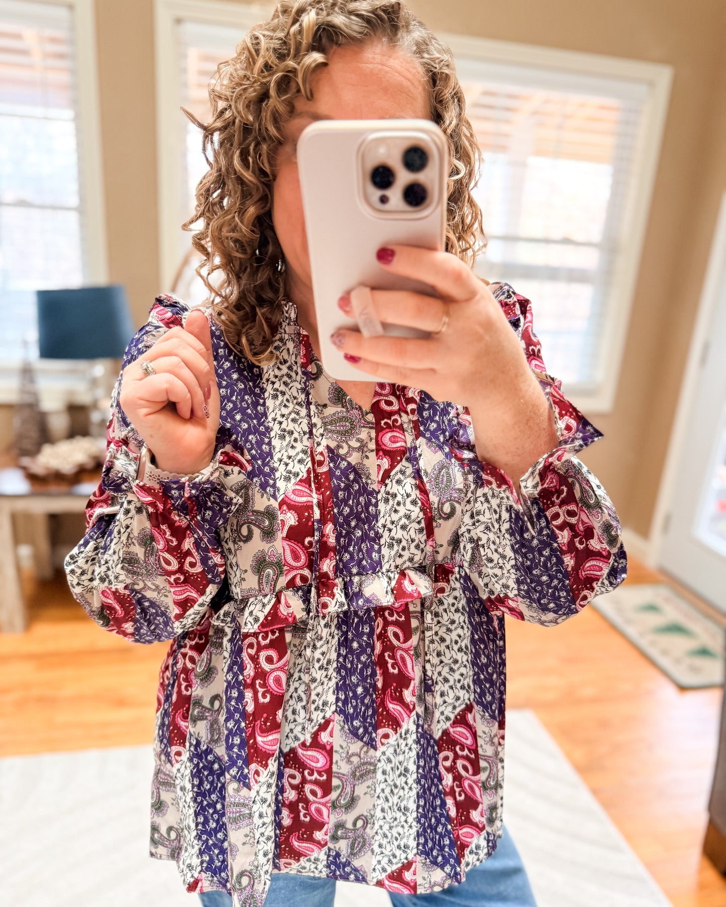 Person wearing a colorful patterned shirt taking a mirror selfie.