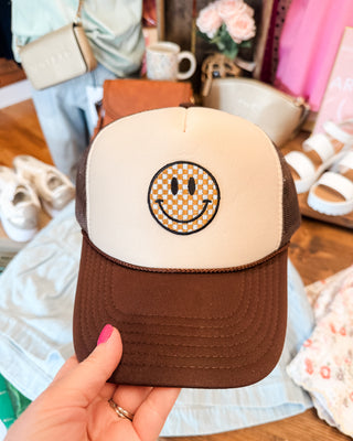 a brown foam trucker hat with checkered smiley face